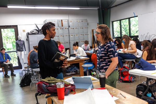 Printmaking professor Laura Post talks to a student in an active classroom